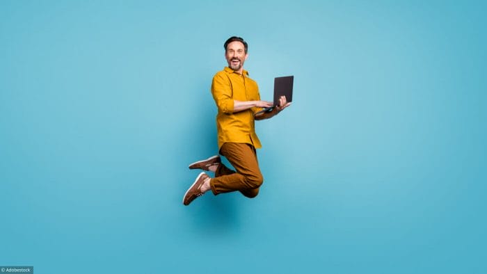 Full size photo of funky man feel rejoice emotions jump use laptop, search social media online black friday discounts wear casual style clothing isolated over blue color background
